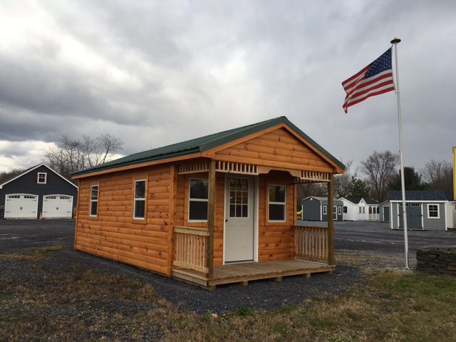 A large wooden cabin with an American Flag on a pole next to it.