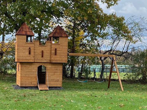 A wooden playset structure in a fenced-in backyard