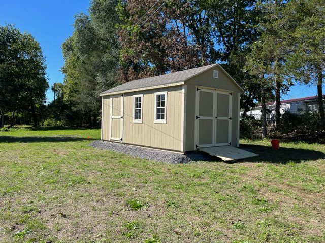 A side view of a tan cottage shed.
